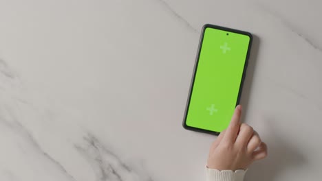 overhead studio shot of child swiping on green screen mobile phone