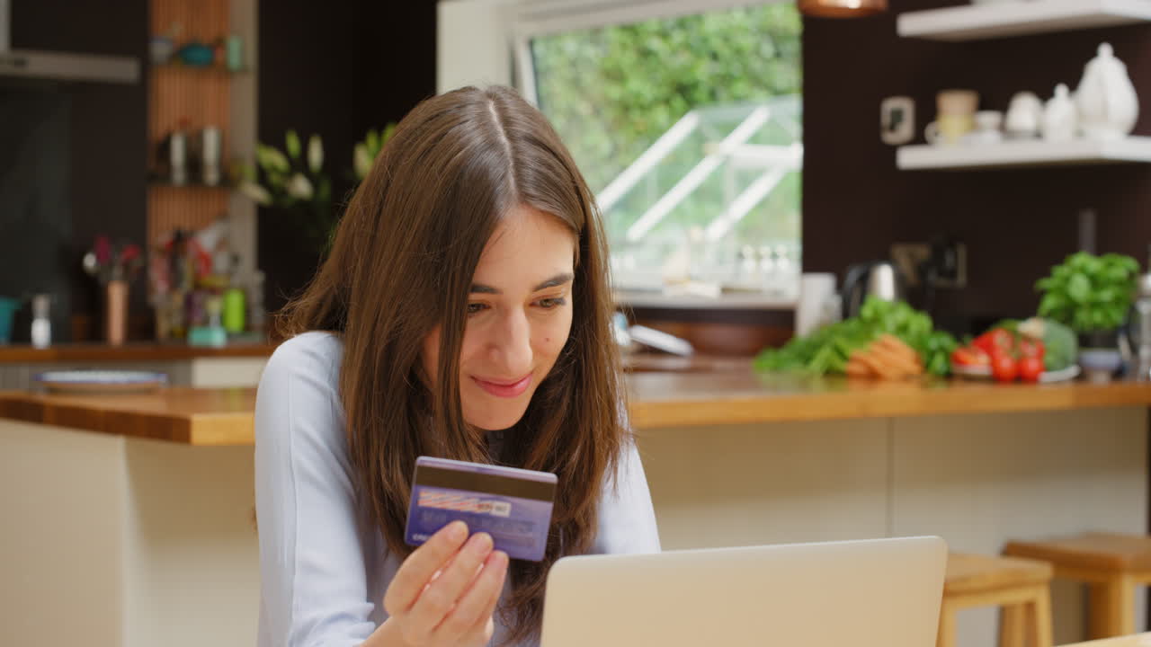 mujer usando portátil y tarjeta de crédito en casa