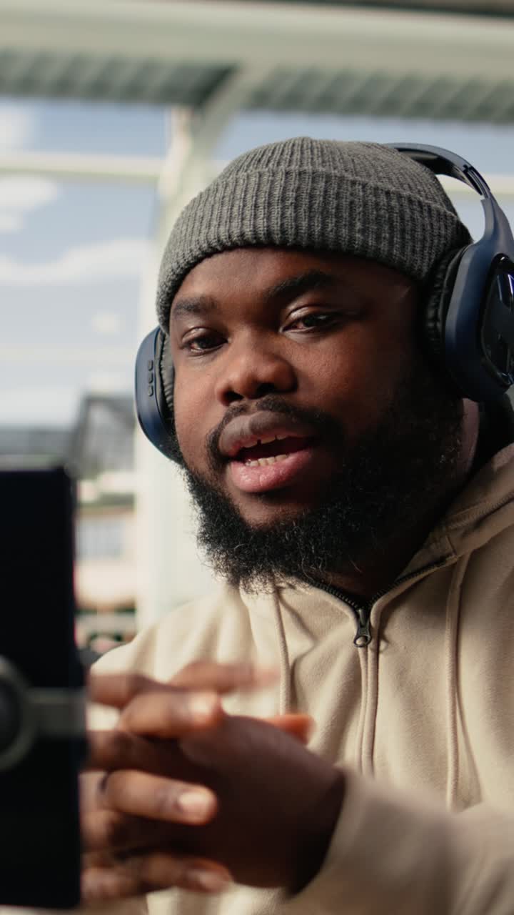 Vertical Video Black man vlogger capturing live broadcast on phone in airport terminal