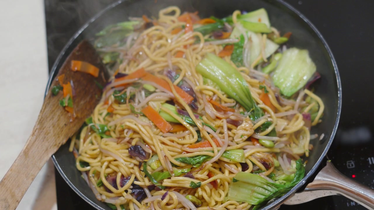Tampilan Atas Mi Goreng Panas yang Baru Dibuat dengan Sayuran Segar termasuk Bok Choi, Wortel. 4K.