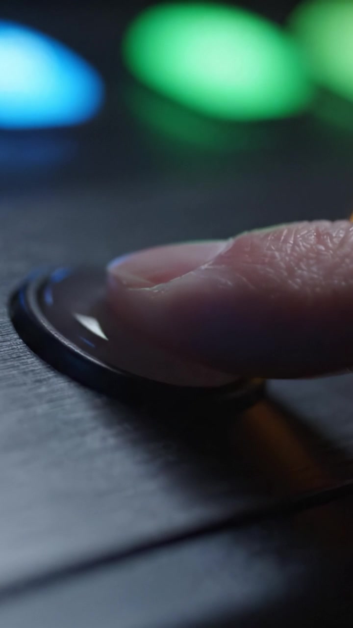 Primo piano di un pulsante rosso vibrante su luci multicolori che brillano delicatamente in uno sfondo scuro e tenue, evidenziando l'estetica del design moderno e la tecnologia.