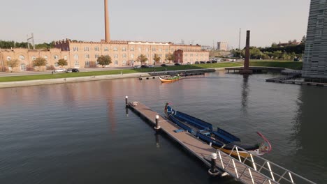 Aerial-dolly-shot-traditional-boat-moliceiro-on-Aveiro-canals,-old-Ceramics-Factory