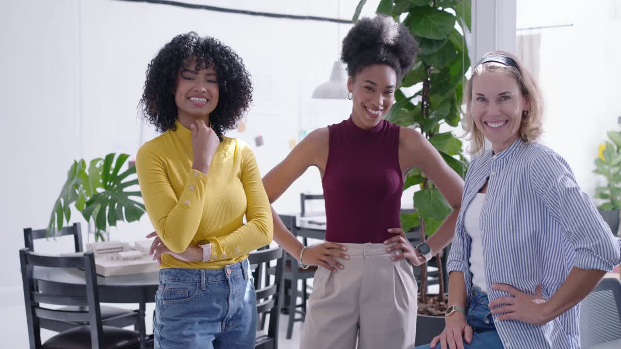 Colegas de trabalho diversas rindo e posando depois que a mulher do centro contou uma história na mesa com laptop.