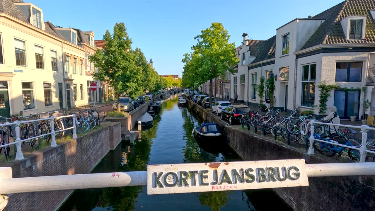 Daytime canal scene with bicycles, boats, historic architecture, and bright natural lighting, static perspective