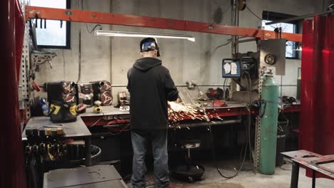 slow mo, blue collar worker grinding metal, sparks flying in metal fabrication workshop