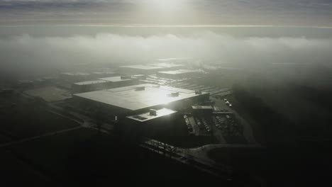 Aerial-shot-of-a-large-factory-building-in-the-morning-fog-in-the-Netherlands