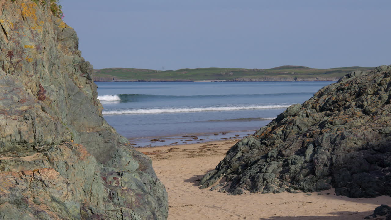 Wide shot Between rocks of the beach at Llanddwyn beach and at the Newborough National Nature Reserve
