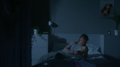 hombre usando el teléfono en la cama por la noche
