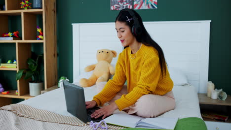 woman using laptop in bed with headphones