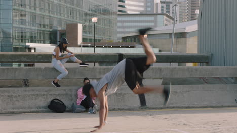 Hombre-Bailando-Joven-De-Raza-Mixta-Bailarín-Callejero-Hombre-Breakdance-Movimientos-De-Estilo-Libre-Realizando-Soporte-De-Mano-Amigos-Mirando-Usando-Un-Teléfono-Inteligente-Tomando-Video-Disfrutando-Del-Baile-En-La-Ciudad