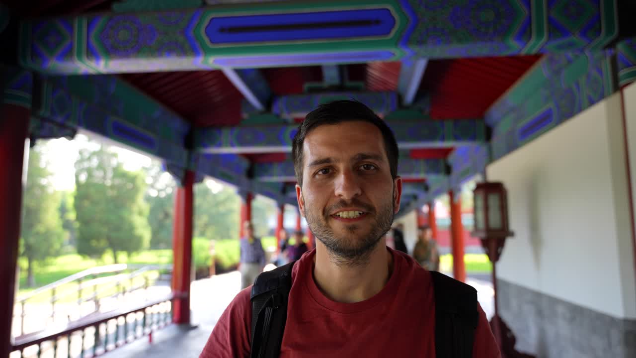 hombre alegre saludando nihao o hola bajo un corredor colorido en beijing, slowmo