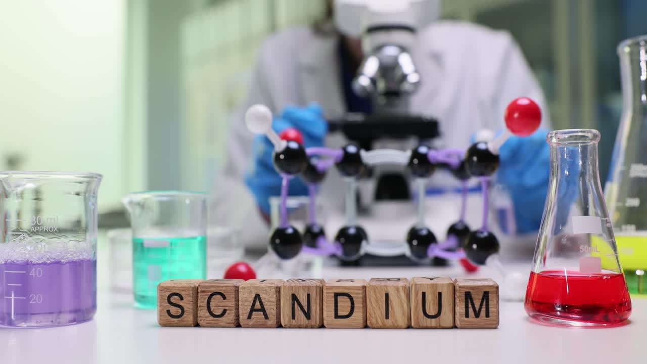 Blocchi con la parola Scandio su un tavolo da laboratorio con uno scienziato