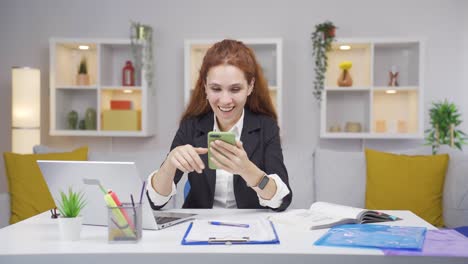 Woman-working-from-home-enjoys-mobile-apps-on-phone.