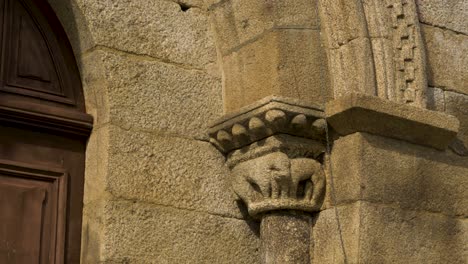 telefoto de primer plano de la entrada de piedra tallada con un animal áspero como una estatuilla junto a la puerta de madera de santa maría de punxin en ourense, galicia, españa