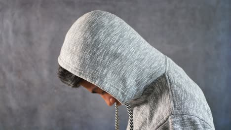 Hombre triste en la cara de la cubierta del capó con las manos aisladas en negro