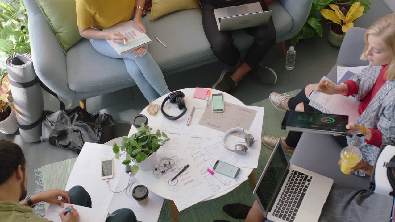 young engineers developing fitness app software using digital tablet computer brainstorming design solution sharing ideas in startup office meeting top view