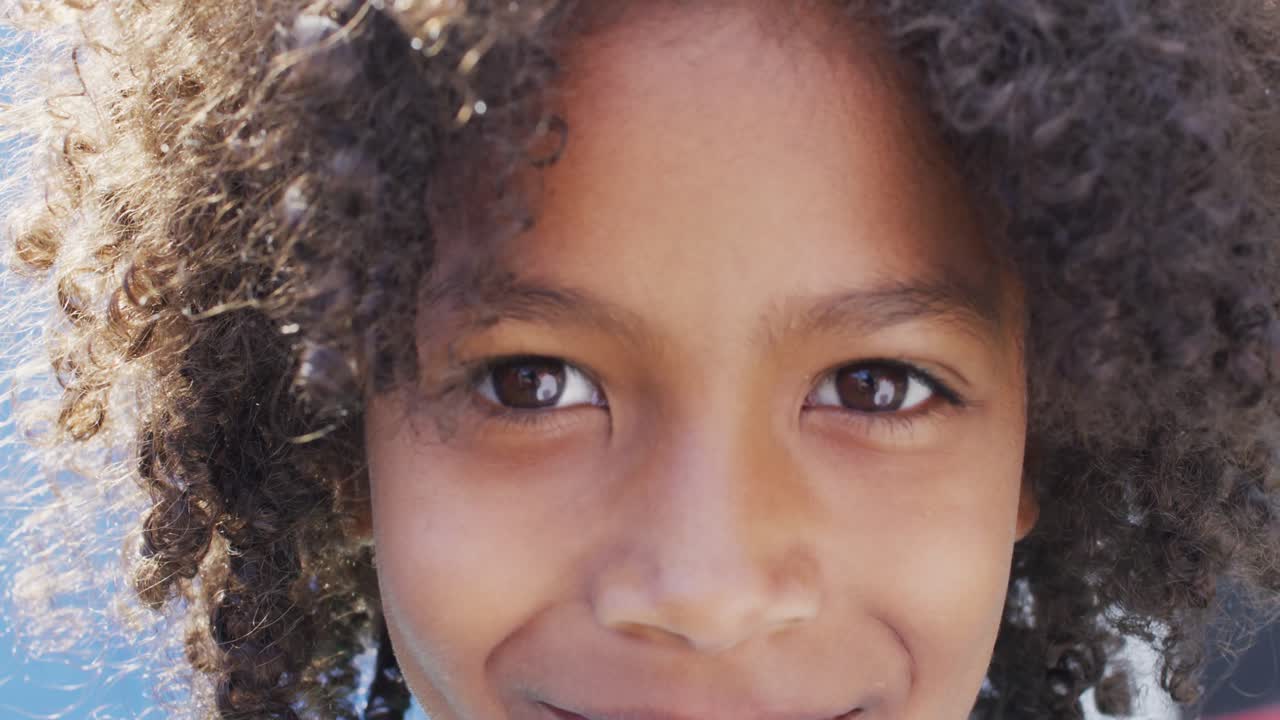 retrato de una feliz estudiante afroamericana mirando a la cámara en el patio de recreo