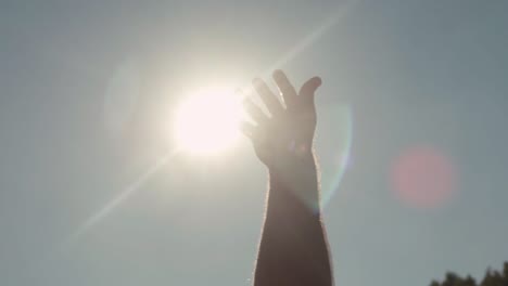 hand reaches towards the sun