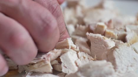 close up on male hands with finger tattoo, chopping - preparing fresh cooked chicken pieces for nutritious, healthy meal