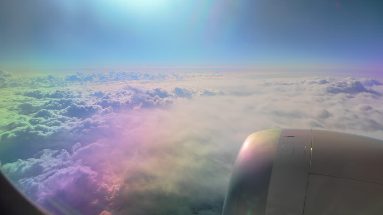 A colorful sky and cloudscape seen from a plane, featuring the aircraft engine and bright sunlight