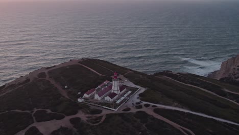 Flying-backwards-at-Farol-do-cabo-Espichel-Portugal-with-soft-evening-light,-aerial