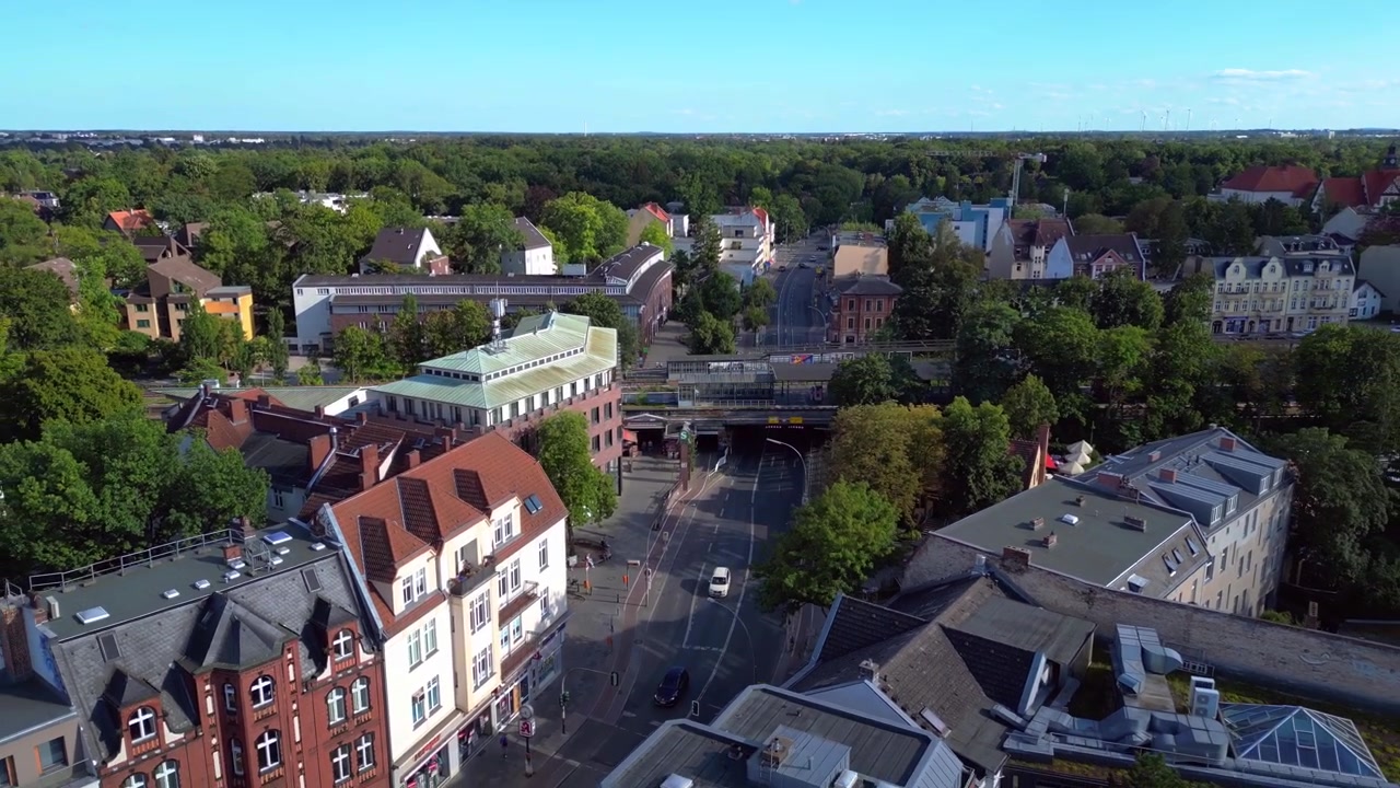 Berliner Vorort Zehlendorf zeigt Gebäude und S-Bahn-Station an einem sonnigen Sommertag. Dramatische Luftaufnahme, Drohnenflug rückwärts.
