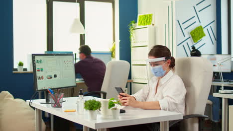 entrepreneur with protective mask typing on mobile phone