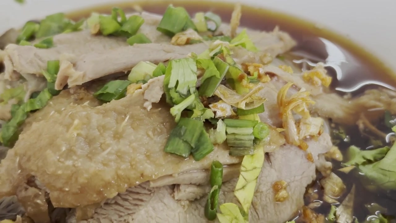 濃厚な黒いスープと米粉麺が入った柔らかい鴨肉のクローズアップ。風味豊かなアジアの麺料理として、温かい丼で提供される。