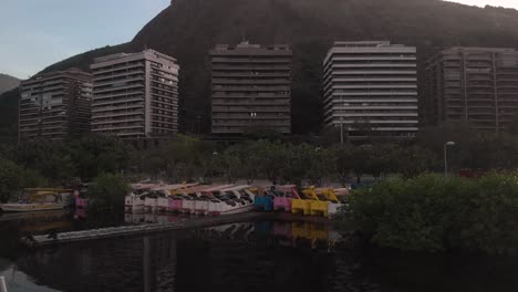 sunrise aerial approach of water bikes on the shore of the city lake in rio de janeiro revealing the corcovado mountain behind the residential neighbourhood mountain range