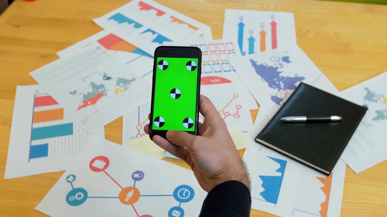 hombre usando teléfono inteligente con pantalla verde en el escritorio de la oficina, espacio de trabajo, buscar información