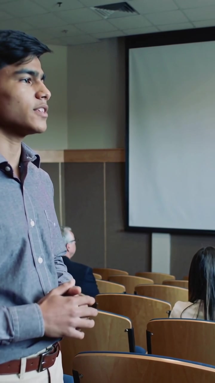 Vertical video: Starting session, speaker in shirt giving talk at class with screen, copy space