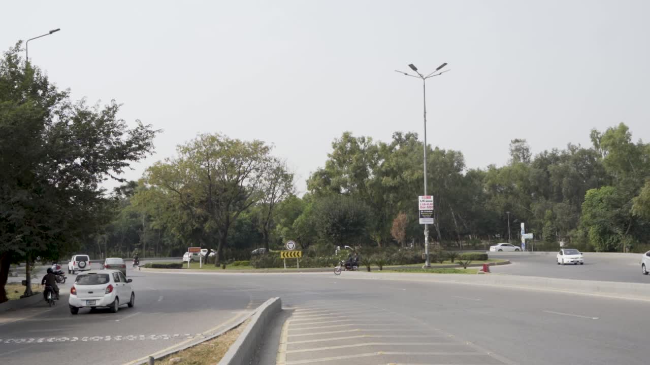 A stunning scene of a circular traffic intersection surrounded by vibrant greenery and cars in motion on their way to their destinations.