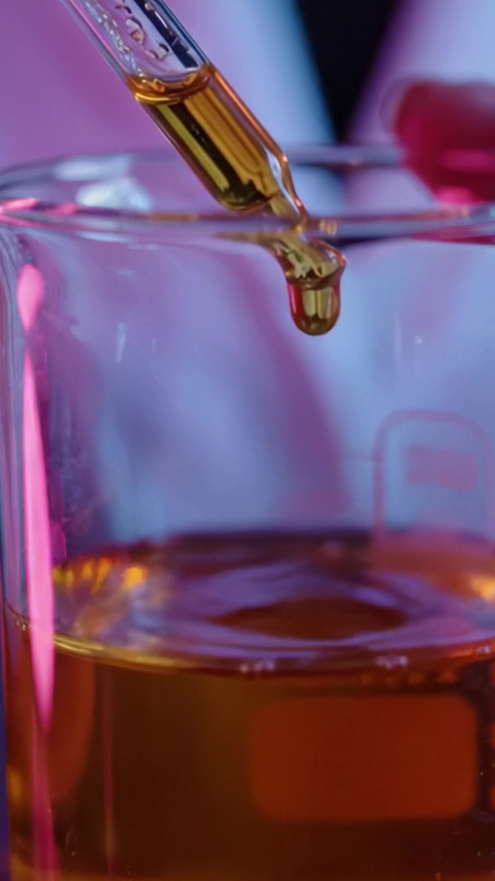 Trasformazione Liquida: Esplorando le complessità della chimica attraverso vividi esperimenti liquidi sotto un'illuminazione colorata in un ambiente di laboratorio.