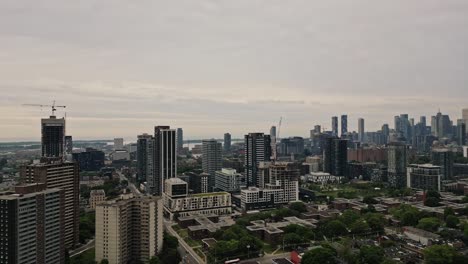 Aerial-Of-Cityscape-Beneath-Dramatic-Cloudy-Sky-At-Sunset