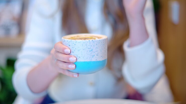 Woman drinking latte art coffee from ceramic cup in a cafe