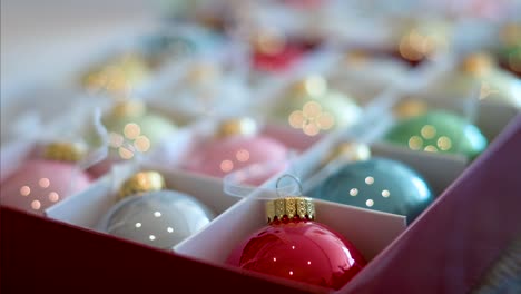 narrow focus on a shiny red christmas tree ball with other colors visible in the box