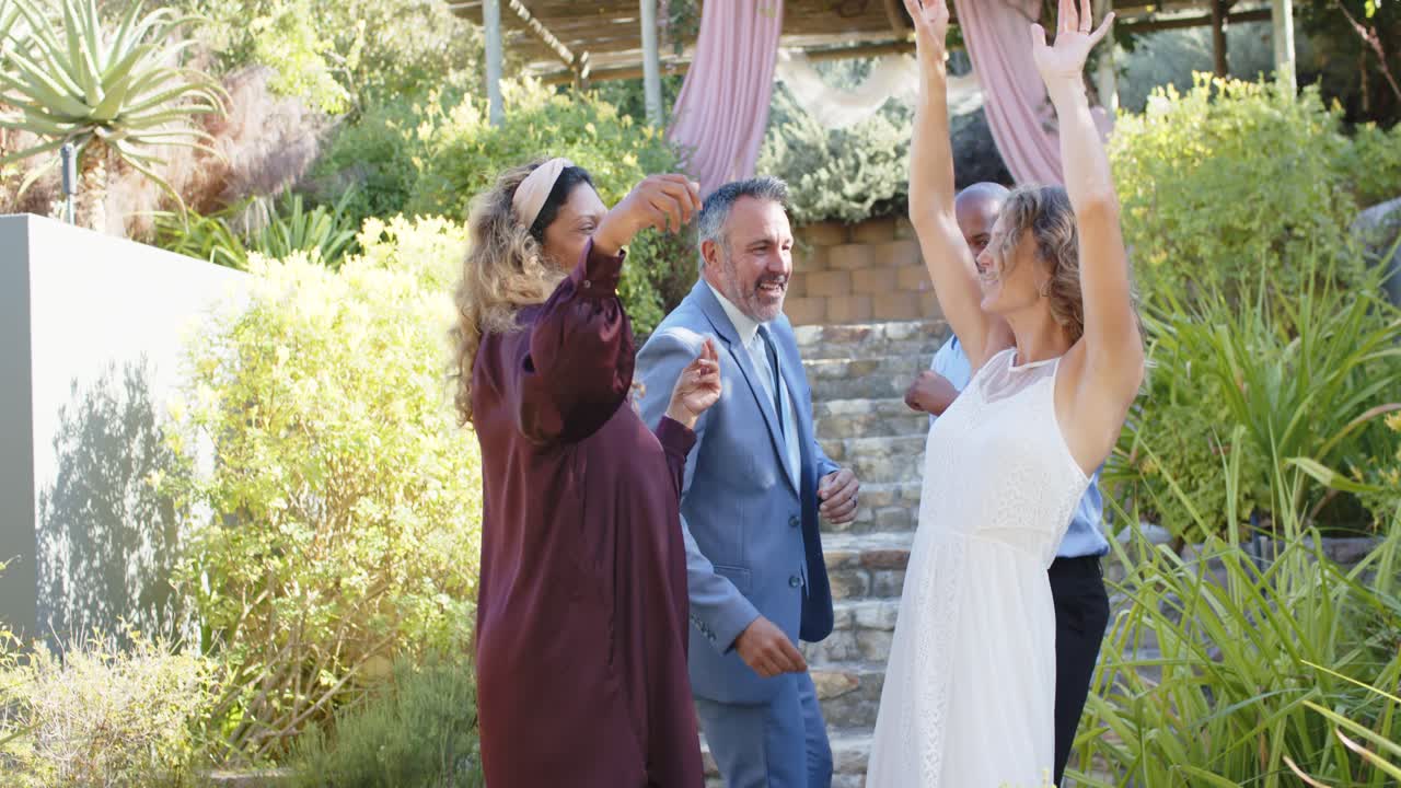 Amici diversi che scendono una scalinata in pietra, festeggiando, ballando, con vestito bianco e vestito viola