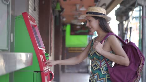 young brunette girl traveler withdrawing money from atm in thailand, asia.