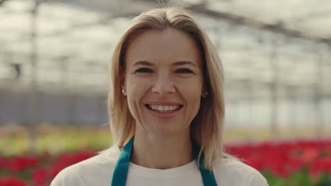 portrait of a smiling blonde woman in a greenhouse
