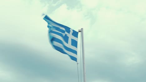 worn greek flag blowing in the wind real time overcast sky