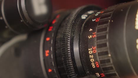 primer plano de los anillos de enfoque y zoom de una lente de cámara de película de 16 mm, que son girados por la mano del camarógrafo