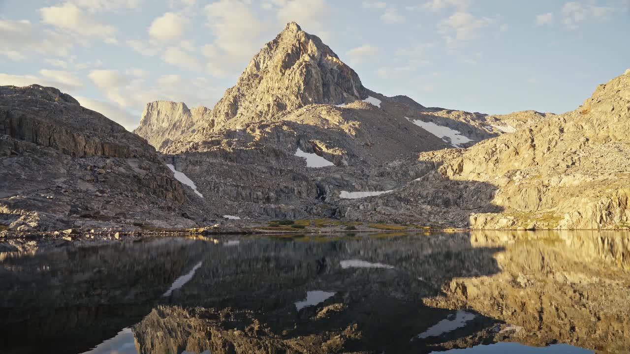 Mountain reflection in a calm alpine lake along the John Muir Trail at golden hour