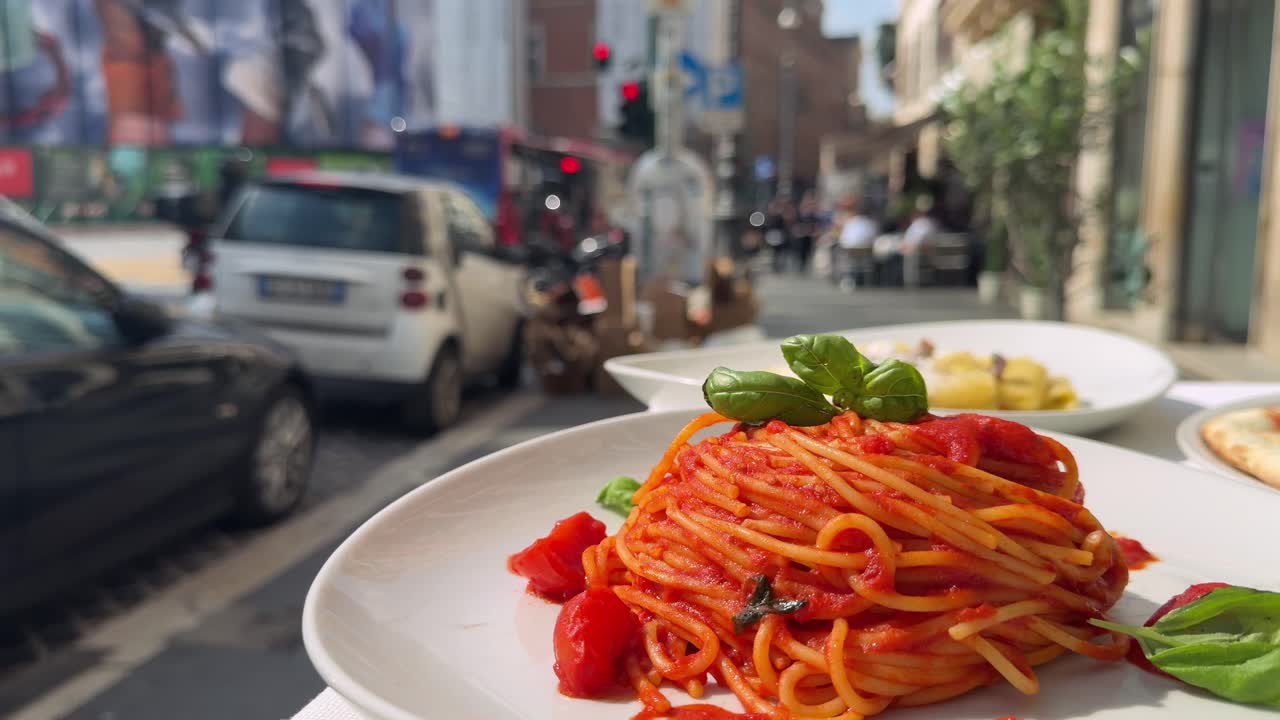 Deliziosi spaghetti con salsa di pomodoro e basilico su una strada cittadina all'aperto.