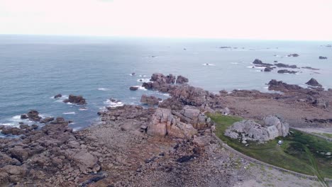 pan drone shot over brittany's shore at low tide showing rocky landscape and houses, france