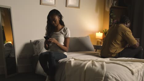 Couple-With-Relationship-Problems-At-Home-At-Night-Both-Looking-At-Mobile-Phones-In-Bedroom