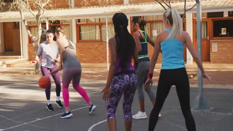 Diverse-female-basketball-team-playing-match,-dribbling-ball
