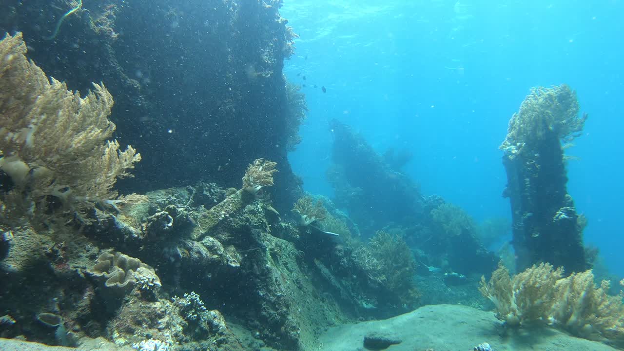 Japanese shipwreck sits on the bottom of  the ocean floor with blue water and live corals, in Amed, Bali, Indonesia