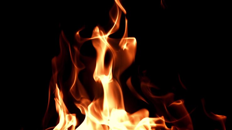 Fiamme arancioni brillanti che bruciano su uno sfondo nero