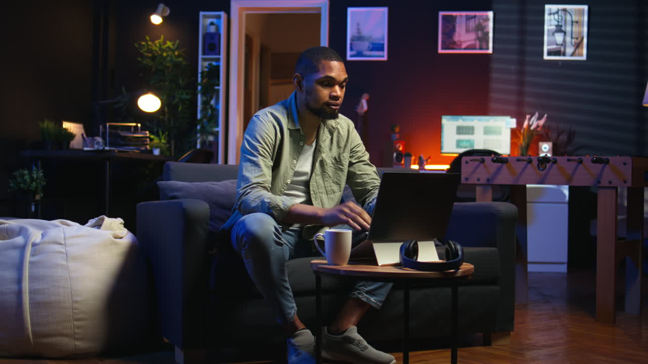 Vertical Video Young black guy working on his freelance tasks in the living room