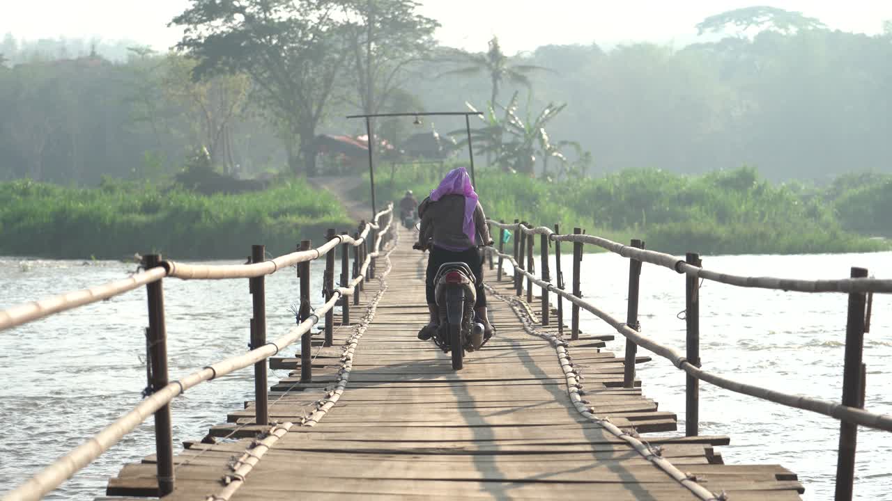 activities of rural people going to work using motorbikes across a bridge made of traditional wood. Big river, Progo river, Kulonprogo.